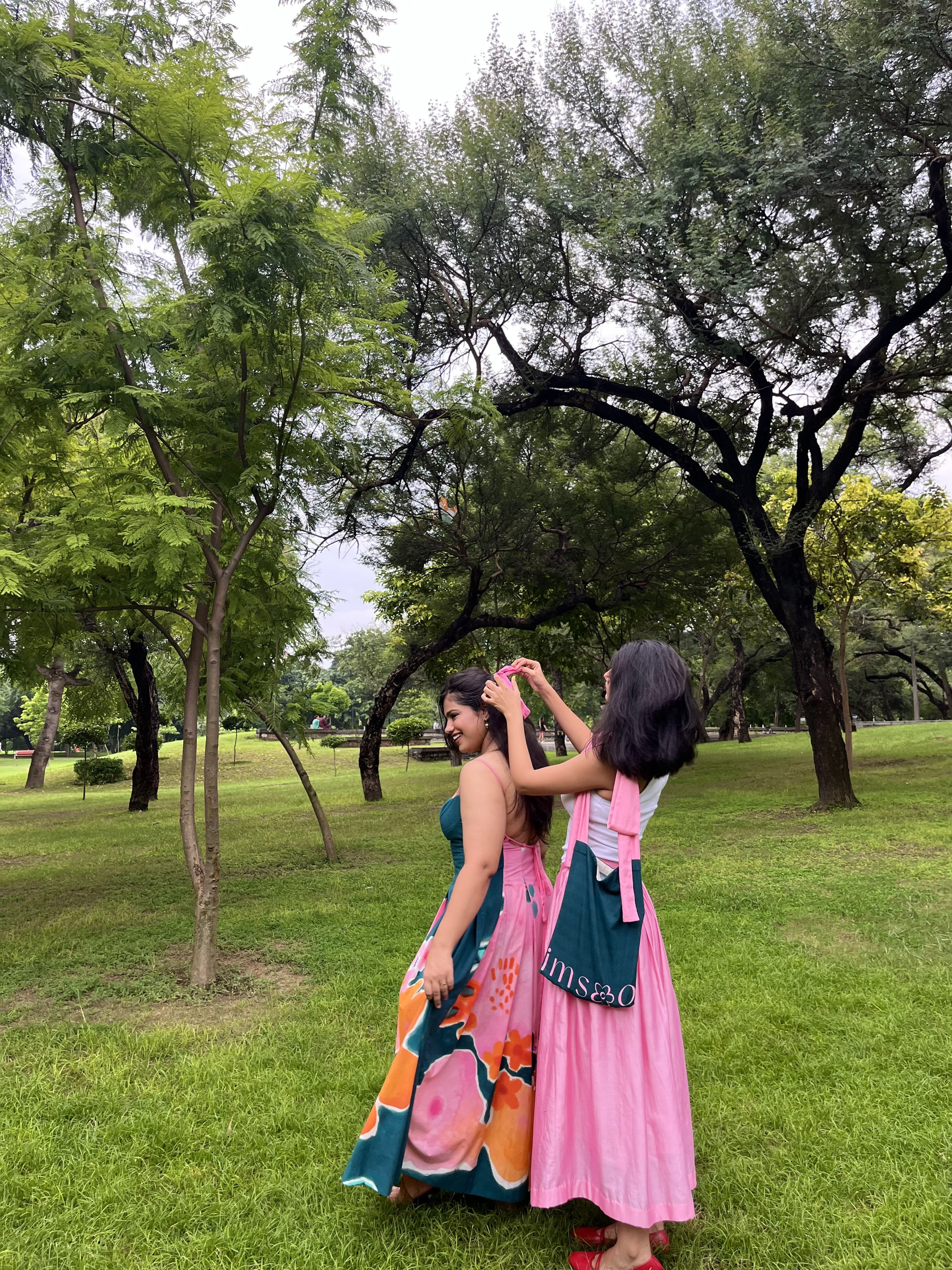 Two women in Imsoo sustainable colorful dresses standing in a park.