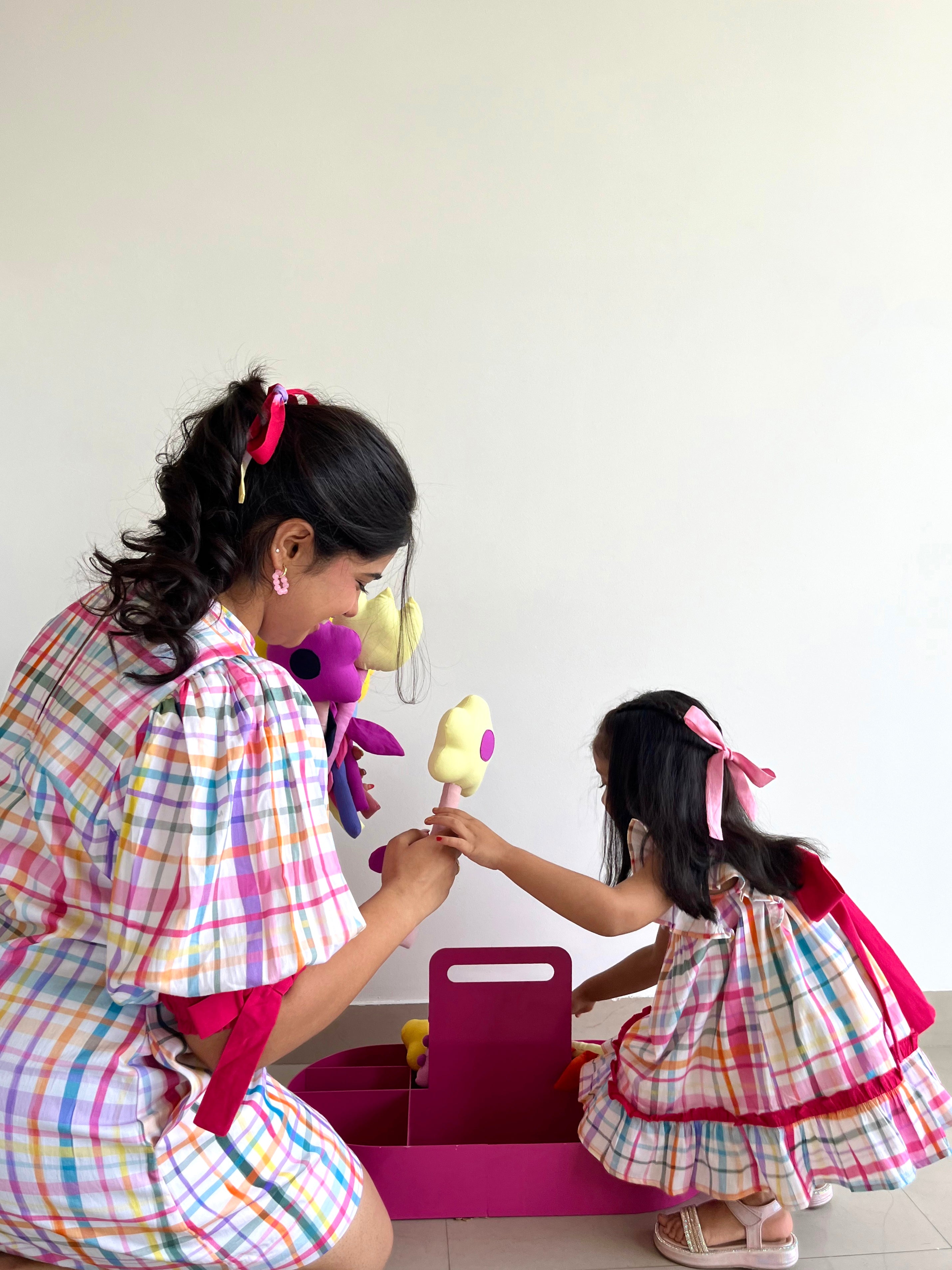 Two children in matching Bubblegum Bow Dress playing with toys.