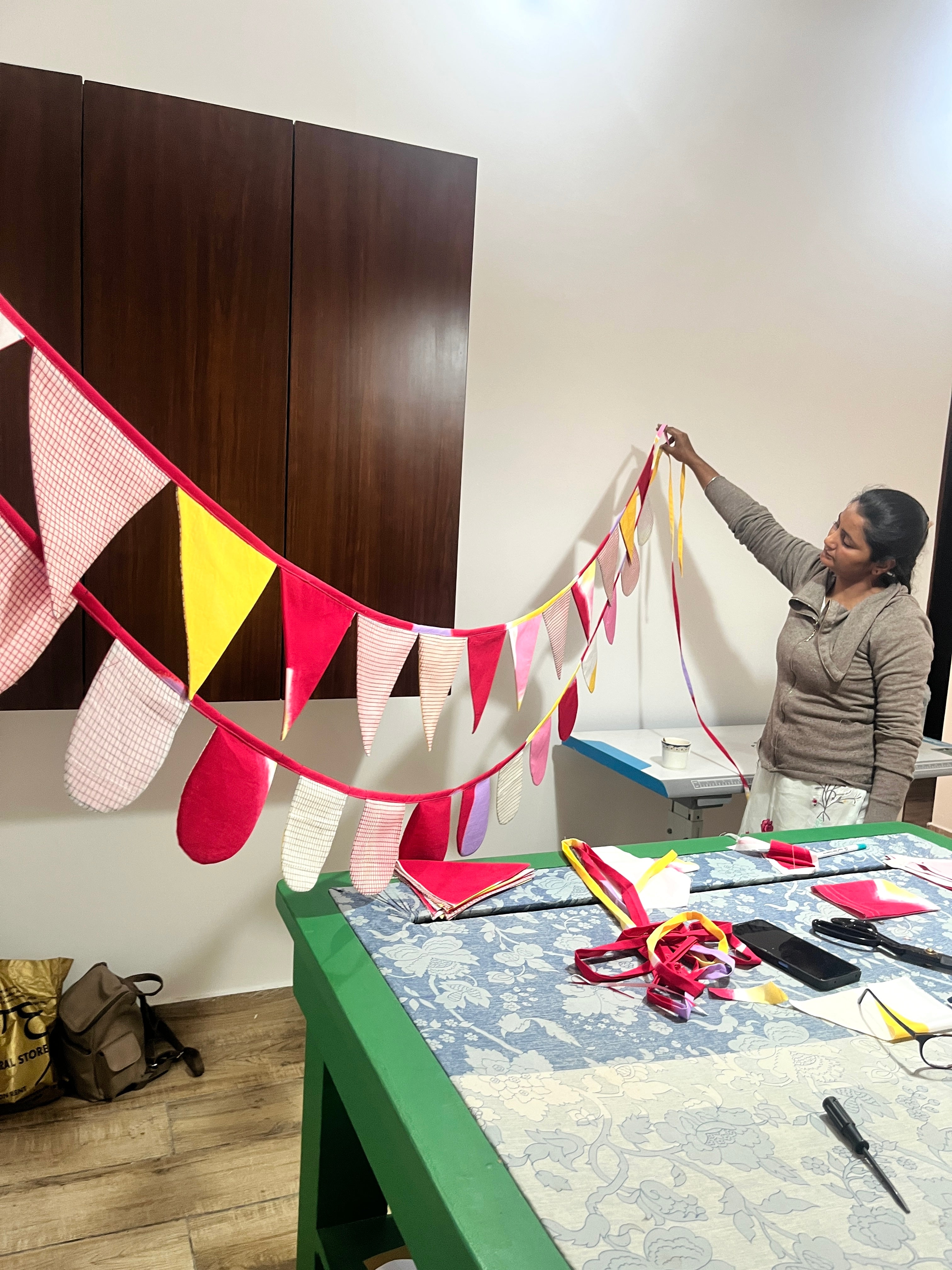 Person hanging colorful fabric decorations on a wall in a room.