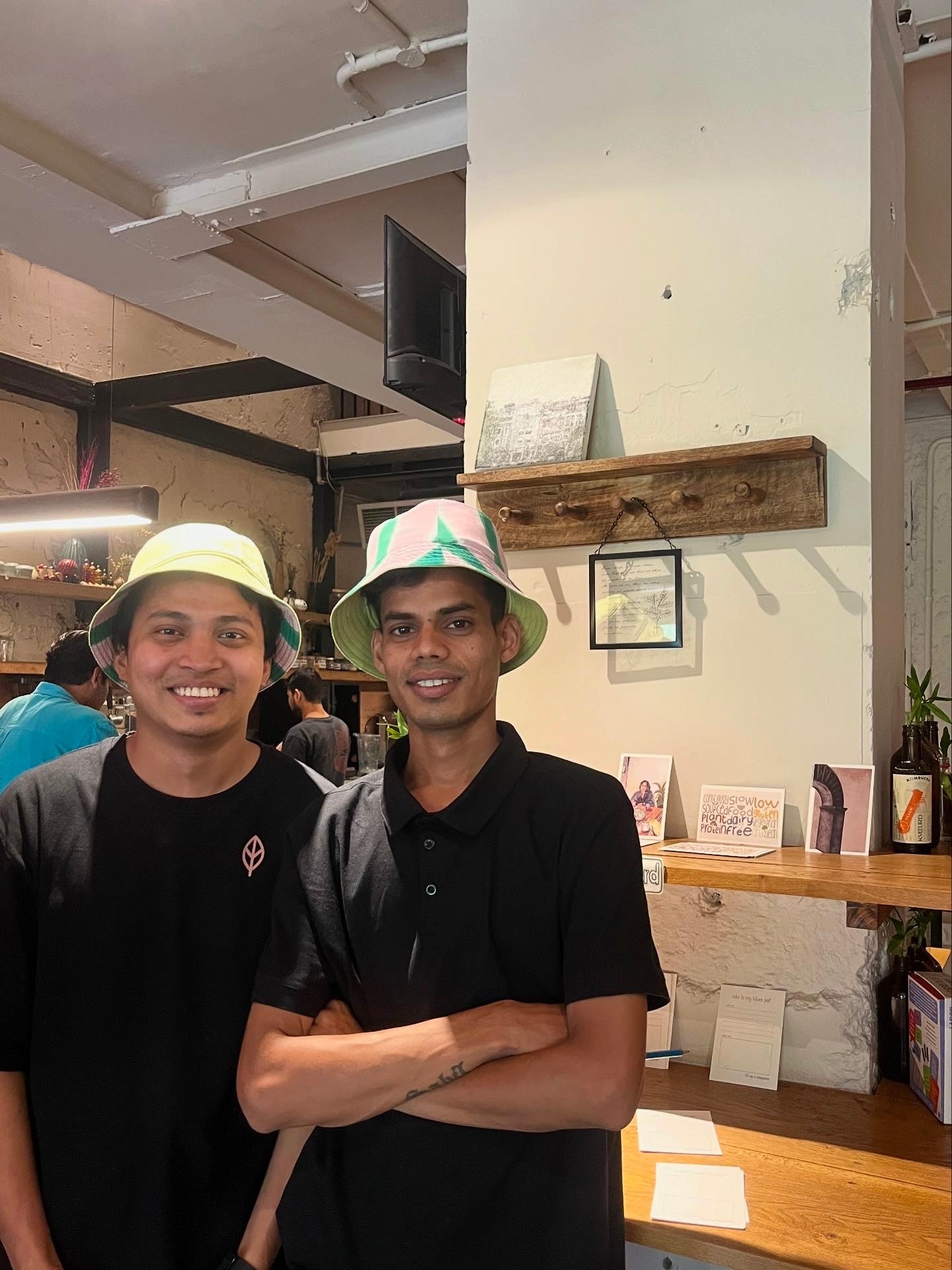 Two men wearing hats standing in a casual indoor setting.