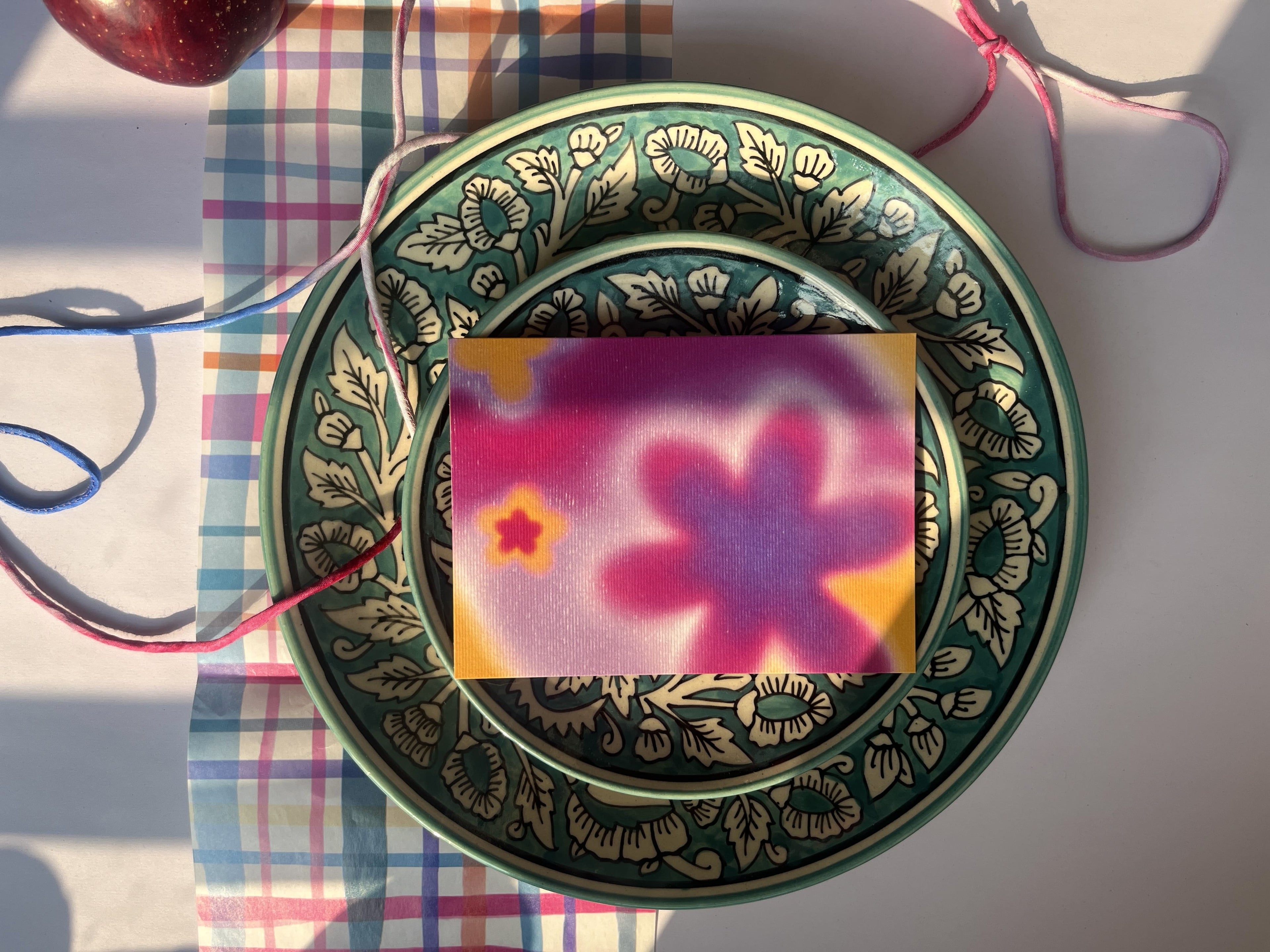 Decorative green plate with floral design on a checkered tablecloth
