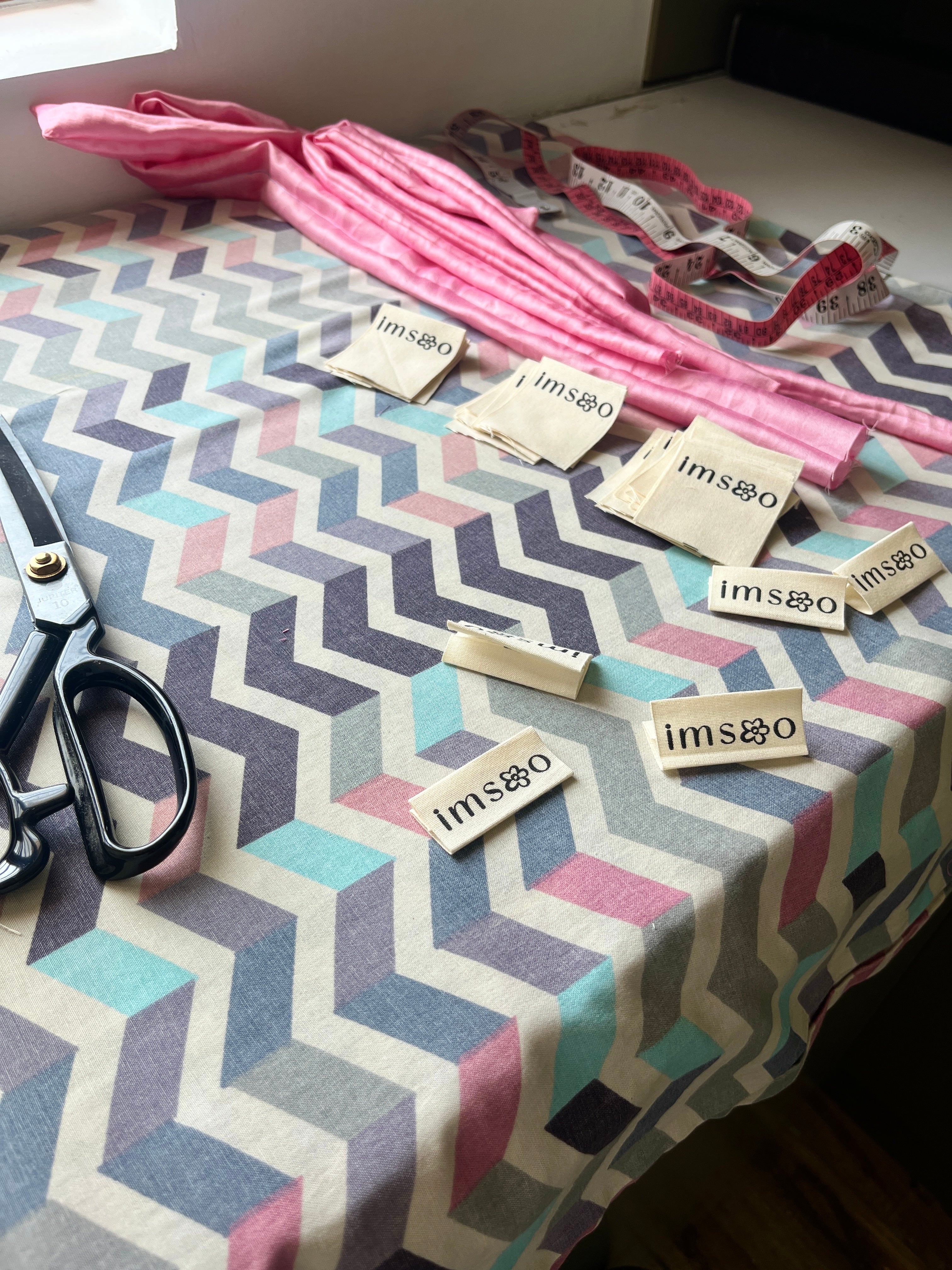 Fabric with zigzag pattern, scissors, and 'Imsoo' labels on a table.